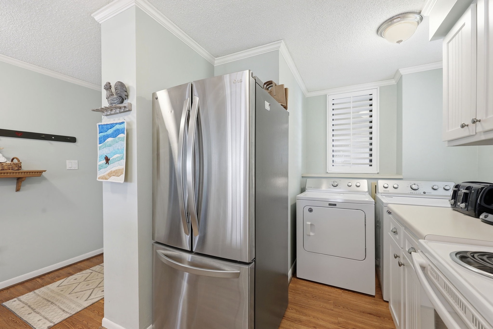 Bright and convenient kitchen corner featuring sleek stainless-steel fridge, in-unit washer and dryer, and modern stove—everything you need for a comfortable stay.