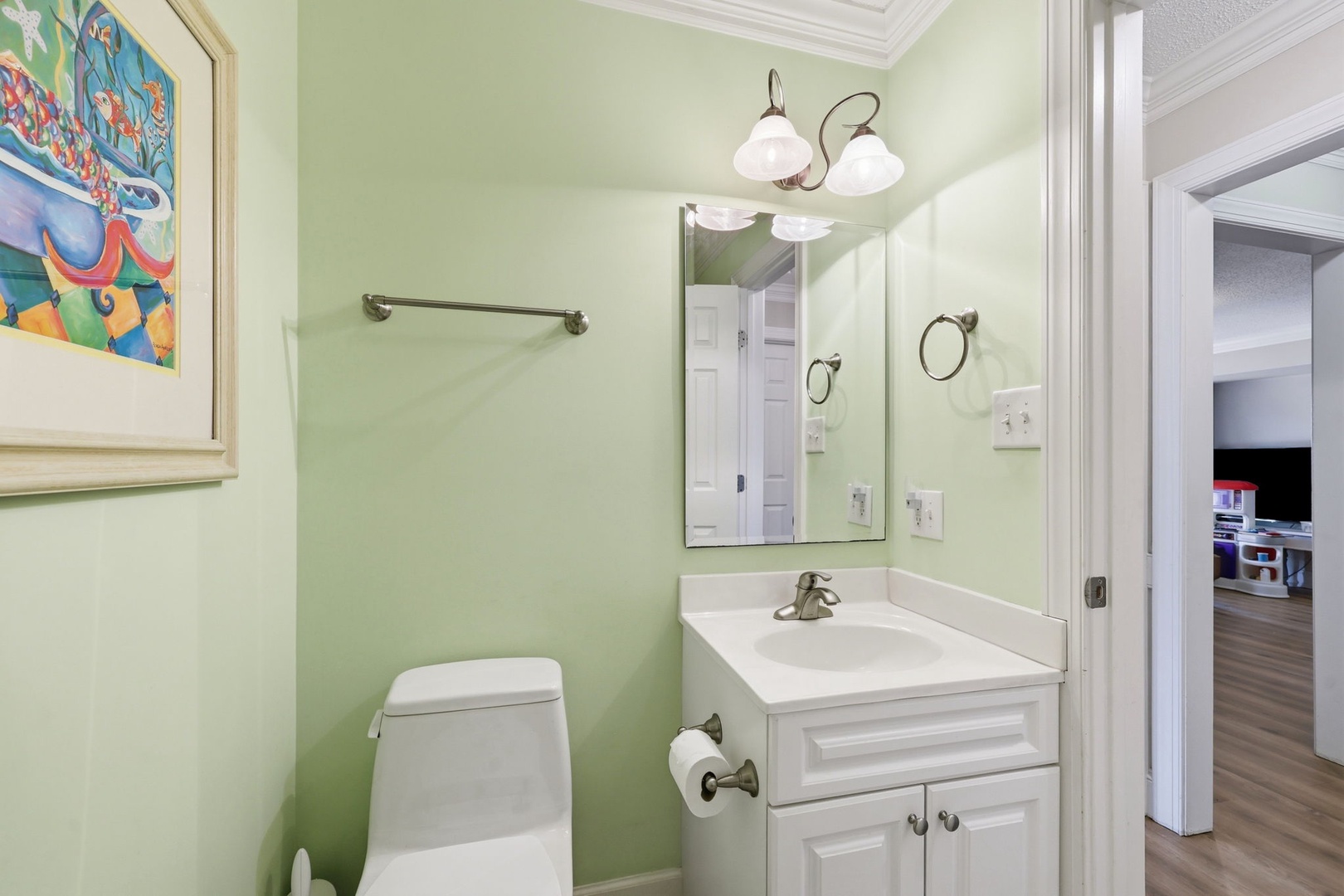 Freshen up in your cheerful bathroom, featuring soft green walls, a clean vanity, and playful artwork that adds charm to your daily routine.