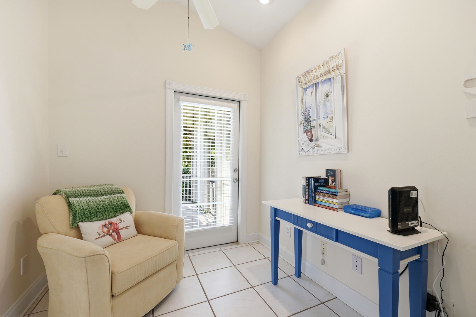 Relax in your cozy reading corner, bathed in natural light from the French door. The soft armchair and charming blue desk create a perfect spot for unwinding with your favorite book.