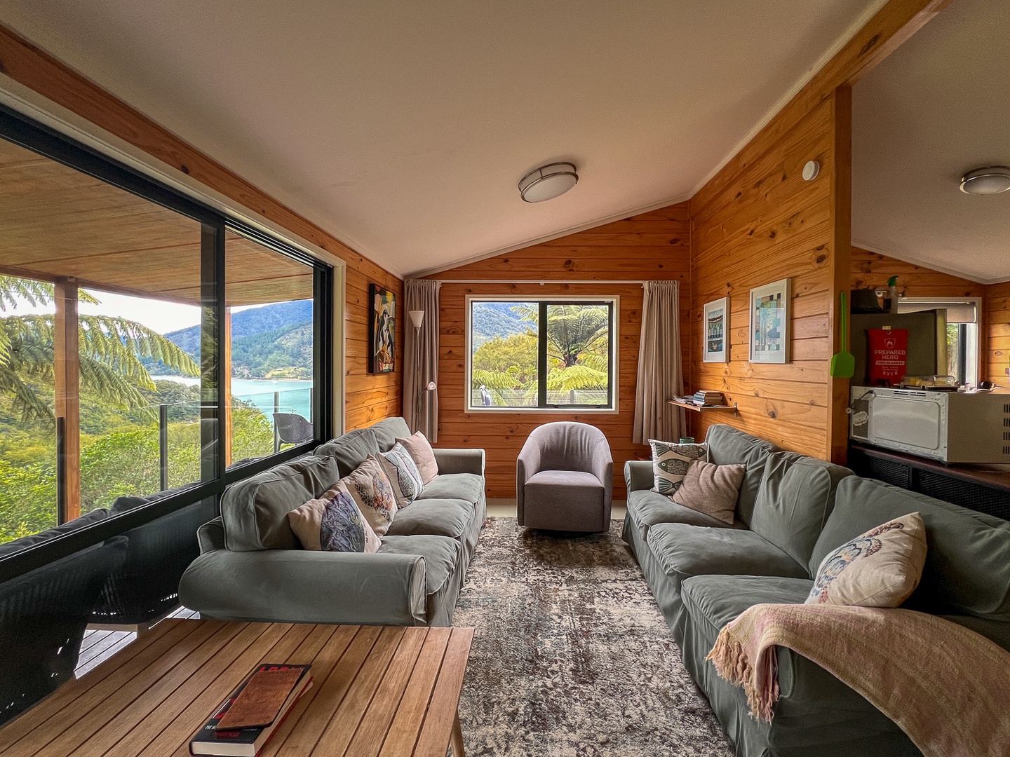 Sink into plush sofas while soaking up stunning lake and mountain views through floor-to-ceiling windows in this cozy wood-paneled retreat.