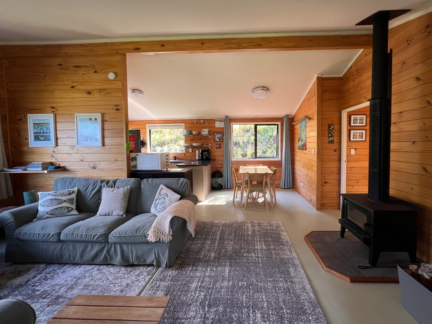 Sink into the plush sofa by the crackling fireplace, surrounded by warm wood walls and natural light streaming through forest views.