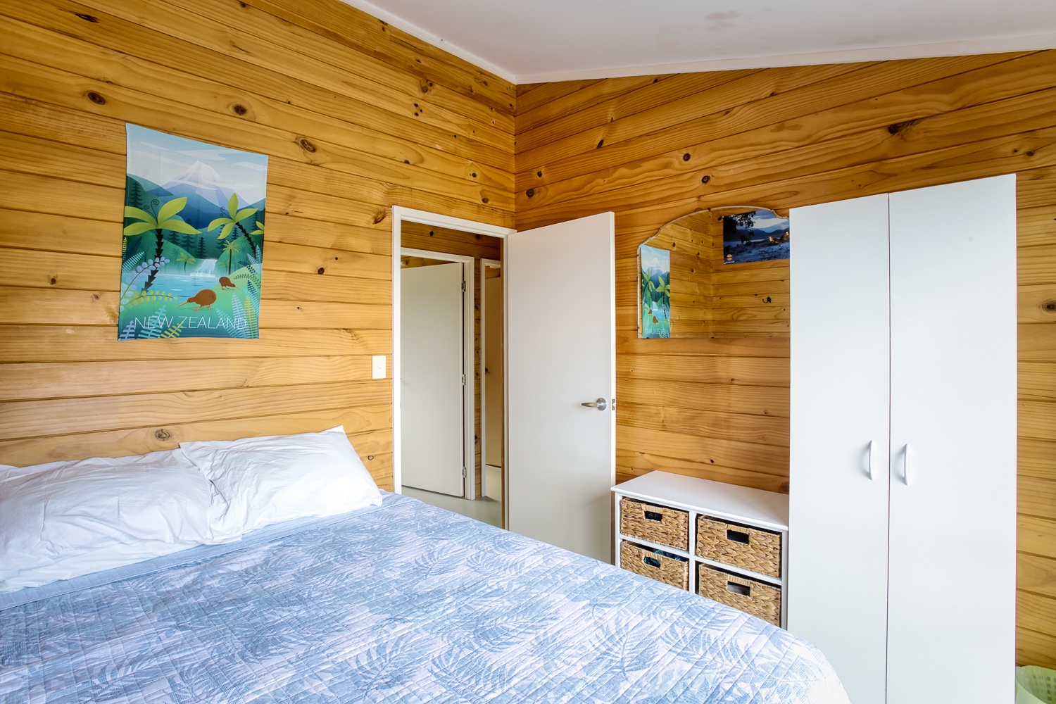 Drift off to sleep in your cozy wooden bedroom where charming coastal art and built-in storage create a peaceful retreat.