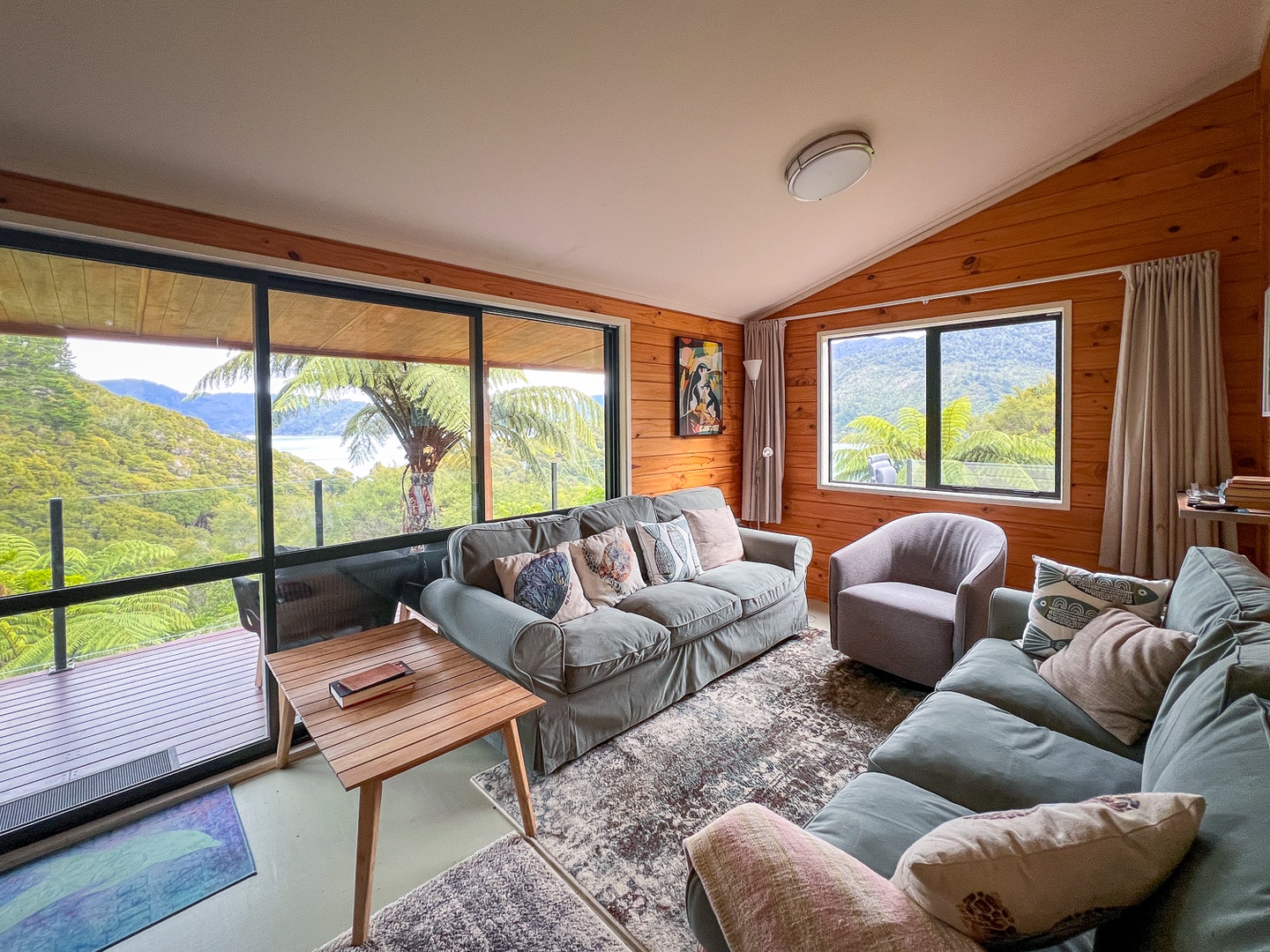 Sink into plush sofas in your mountain retreat, where floor-to-ceiling windows frame breathtaking valley views and warm timber walls create the perfect cozy escape.