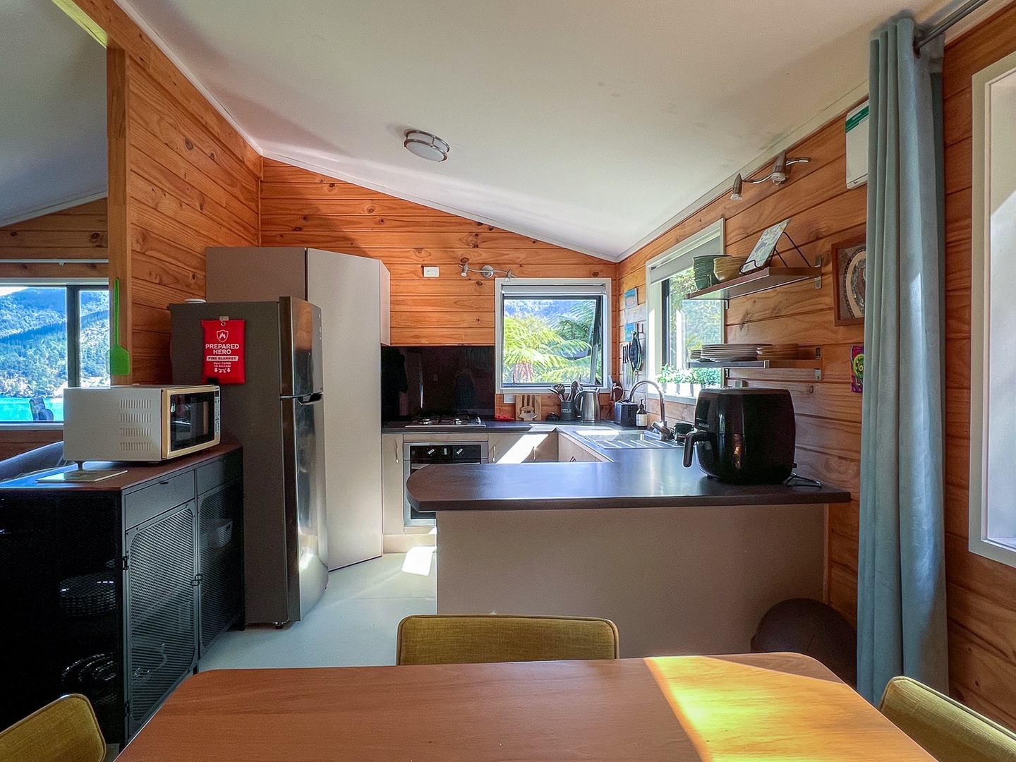 Your fully equipped kitchen features warm wood paneling and mountain views through bright windows, perfect for preparing home-cooked meals during your stay.