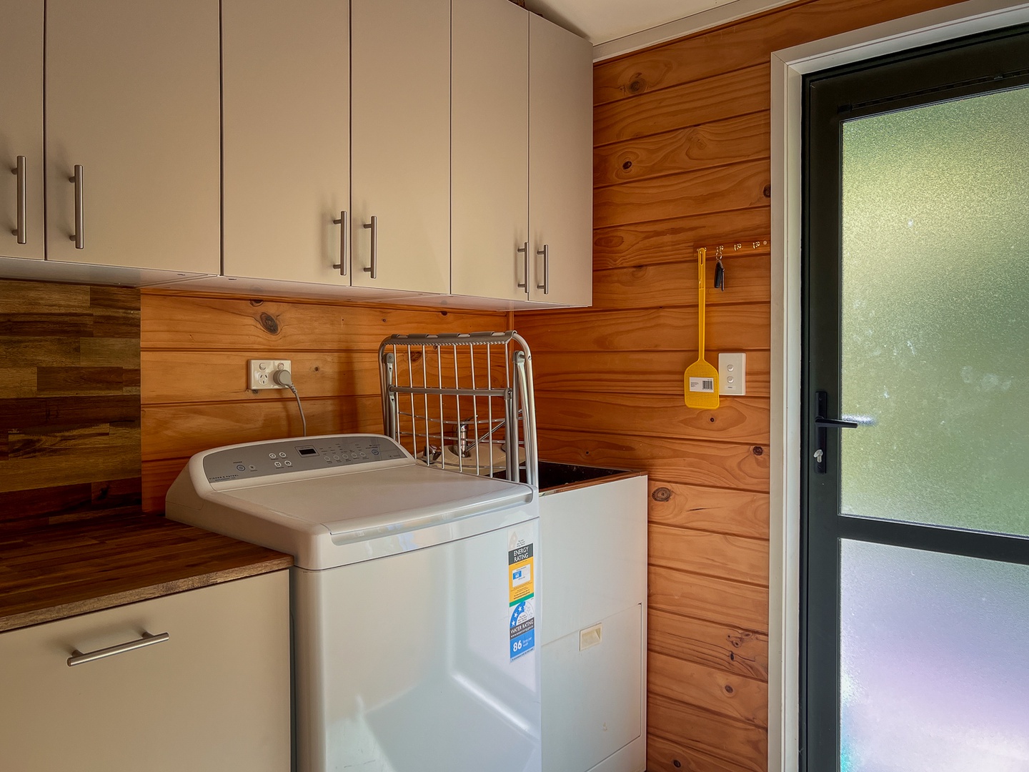 Your dedicated laundry room features a modern washing machine with ample storage above, making longer stays effortless and convenient.