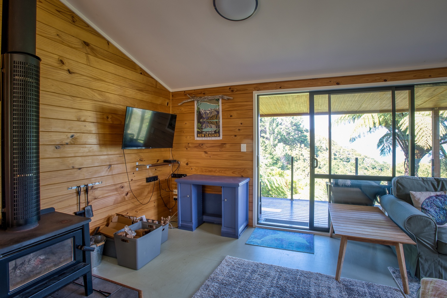 Relax in your cozy living room with warm wood walls, modern fireplace, and stunning forest views through floor-to-ceiling windows.