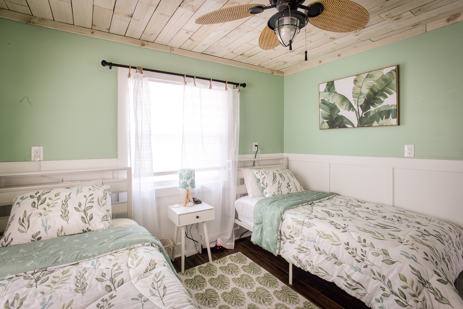 Drift off in your serene twin bedroom, where botanical bedding meets coastal charm under rustic wood beams and gentle sea breezes.