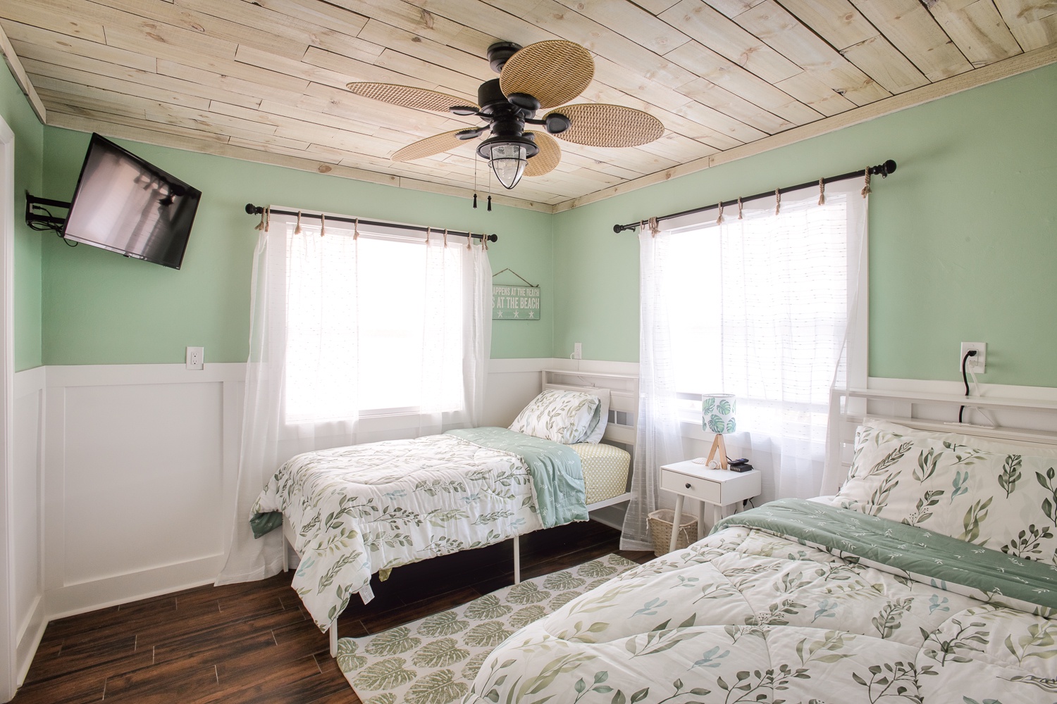 Drift off in your serene twin bedroom with botanical bedding and rustic wood ceiling fan keeping you cool.