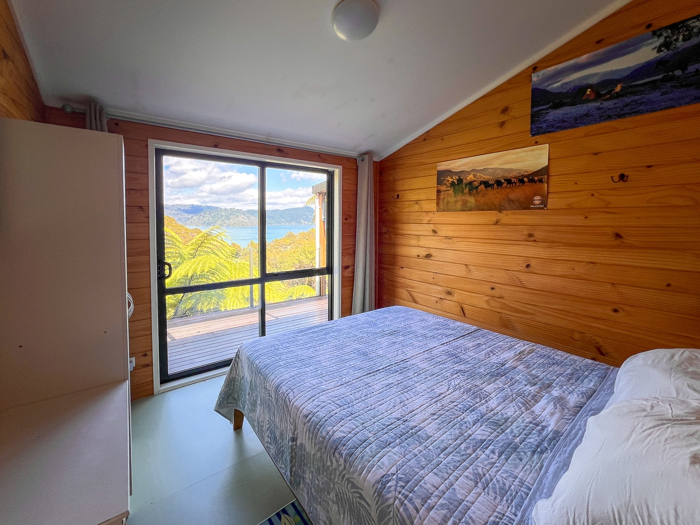 Wake up to breathtaking mountain vistas from your cozy bedroom, where warm timber walls frame panoramic views of rolling green hills and distant peaks.