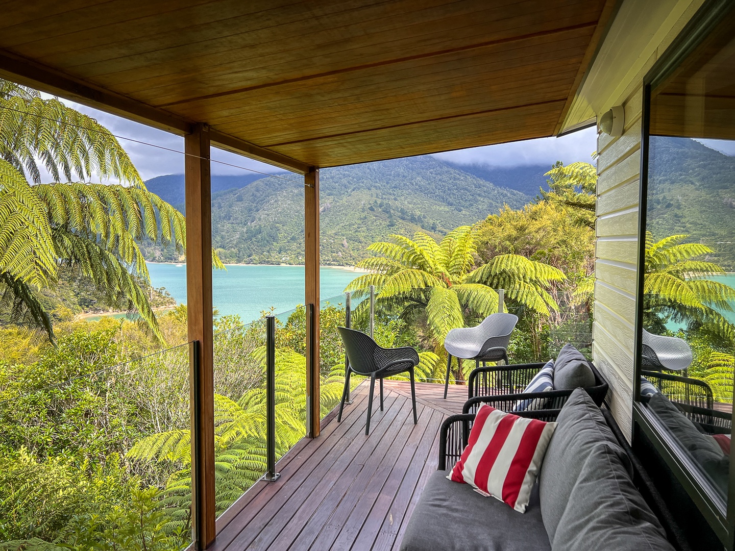 Relax on your private deck overlooking pristine turquoise waters and lush mountains. Your perfect sanctuary awaits with comfortable seating and breathtaking views.