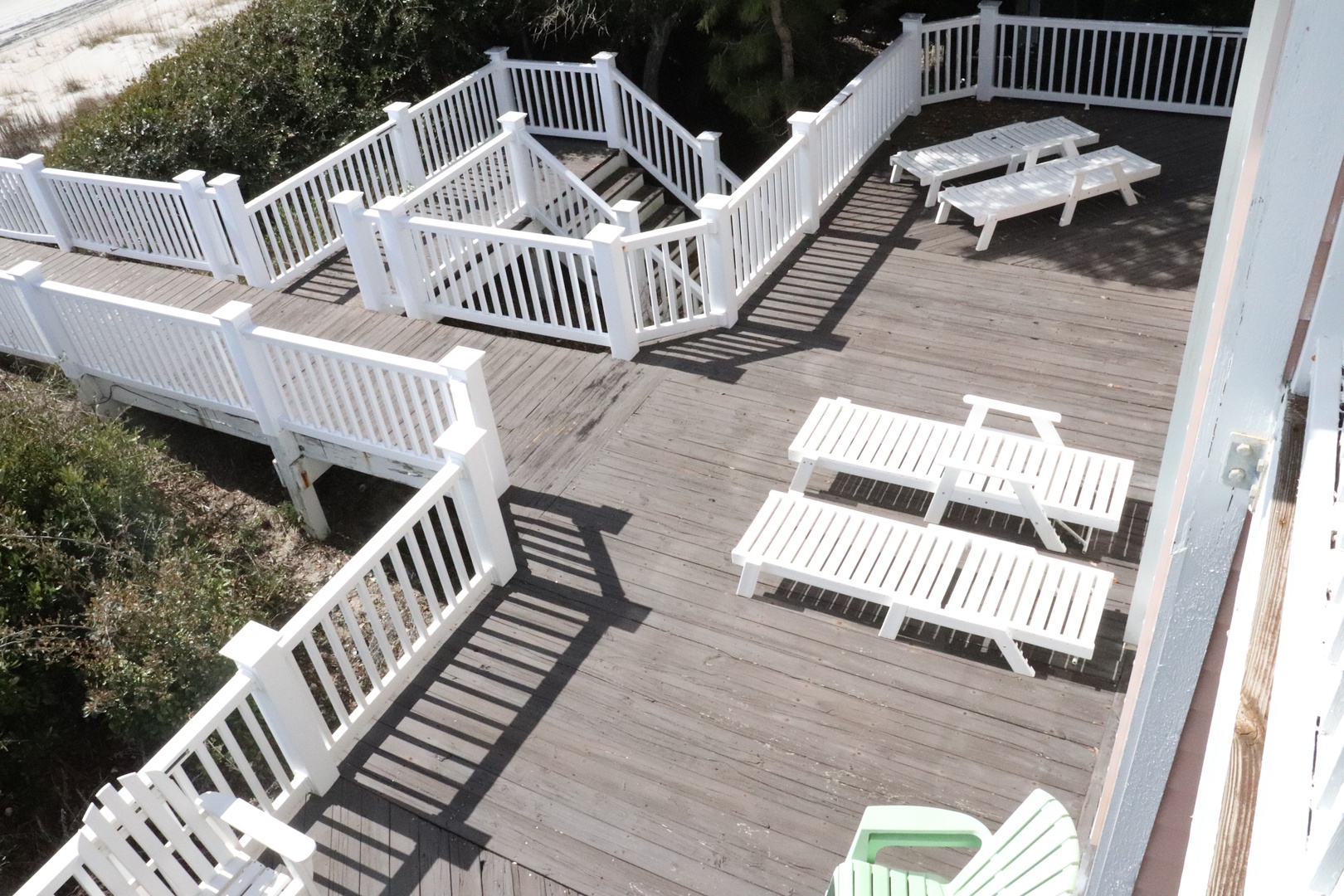 Expansive deck featuring white railings, multiple sun loungers, and picnic tables perfect for outdoor dining and relaxation.
