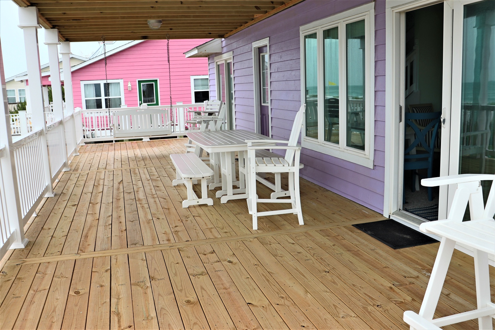 Unwind on your private deck with white outdoor furniture, enjoying the colorful coastal neighborhood backdrop.