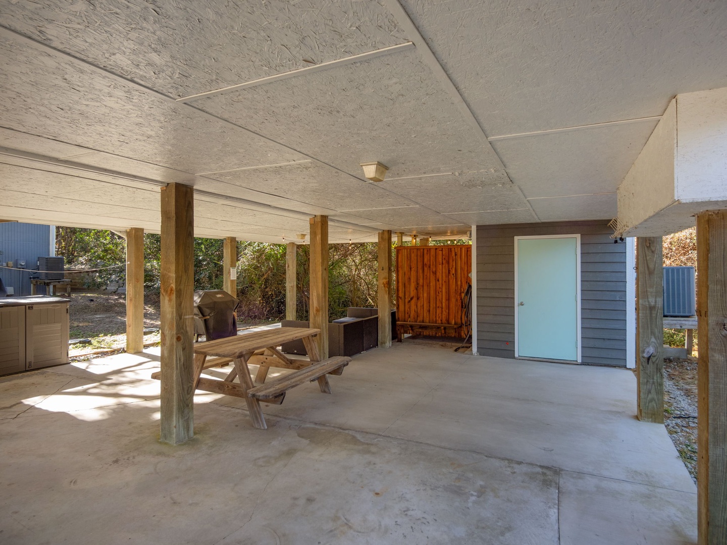 Spacious covered patio with rustic wooden picnic table, perfect for outdoor dining and relaxing in the shade.