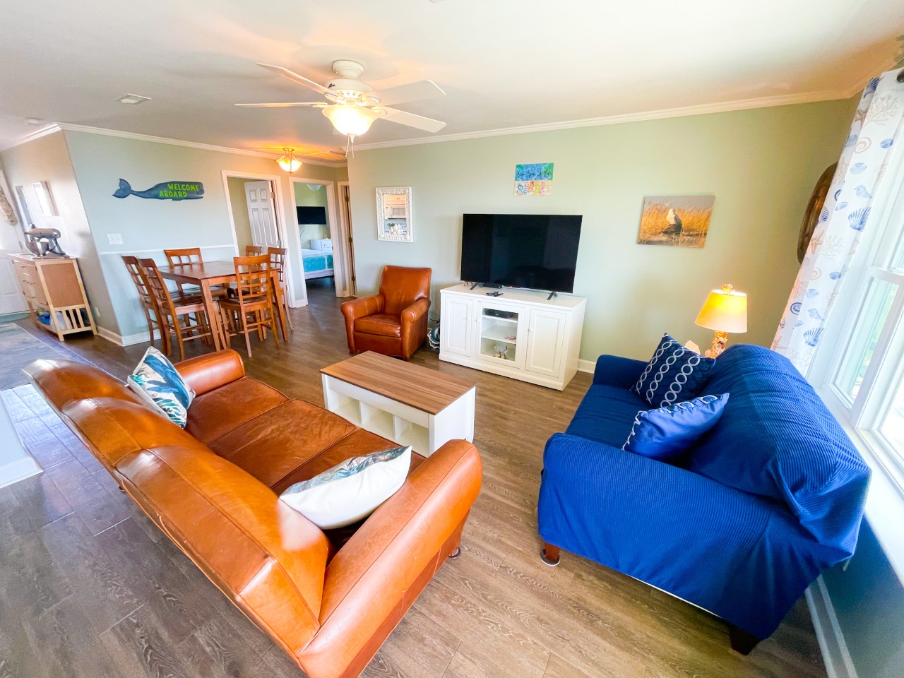 Unwind in your spacious living area with comfortable leather seating, flat-screen TV, and coastal charm that invites relaxation.