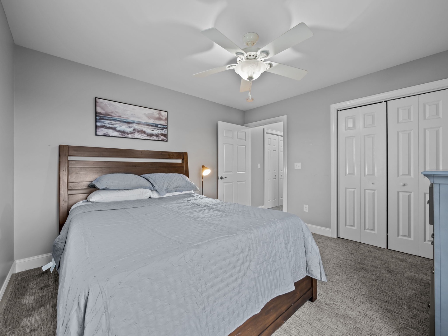 Relax in your serene bedroom with a cozy wooden bed, ceiling fan for comfort, and ample closet storage space.