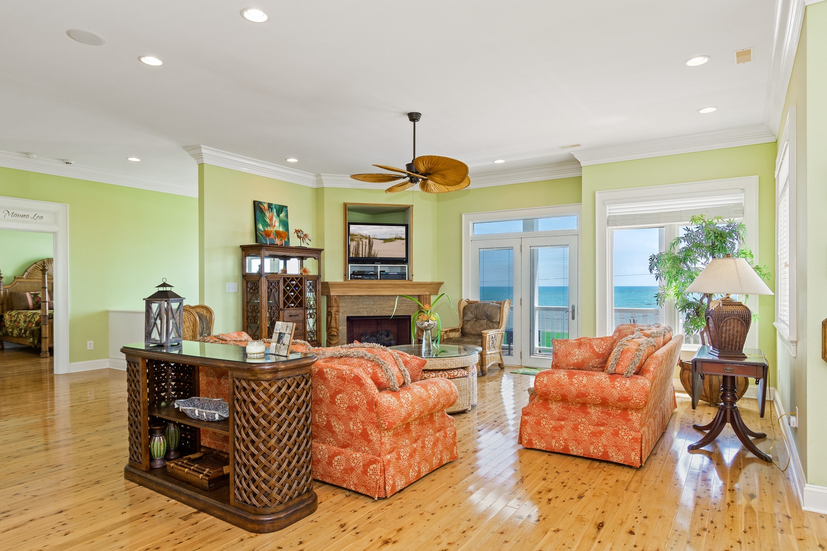 Relax in your bright living room with ocean views, cozy fireplace, and tropical ceiling fan creating the perfect coastal retreat.
