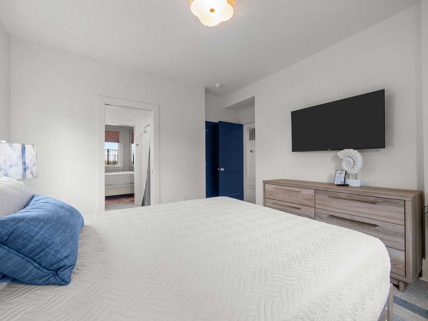 Unwind in your serene bedroom featuring a plush bed, modern dresser, and wall-mounted TV for cozy movie nights after exploring the city.