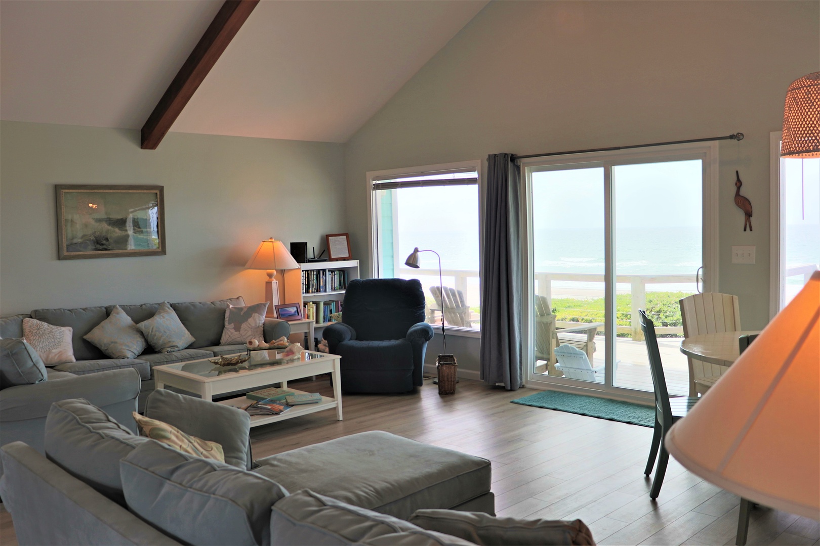 Sink into plush sofas while ocean waves frame your view through floor-to-ceiling windows in this bright, airy living space.