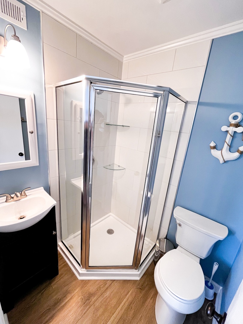 Refresh in your nautical-themed bathroom with spacious glass shower, modern vanity, and charming coastal touches that make morning routines feel like seaside escapes.
