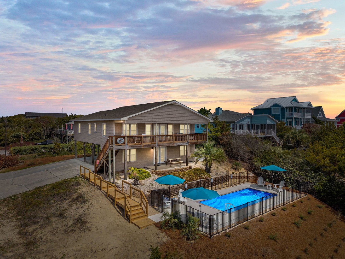 Elevated beach house with private pool and deck surrounded by coastal vegetation under dramatic evening sky.