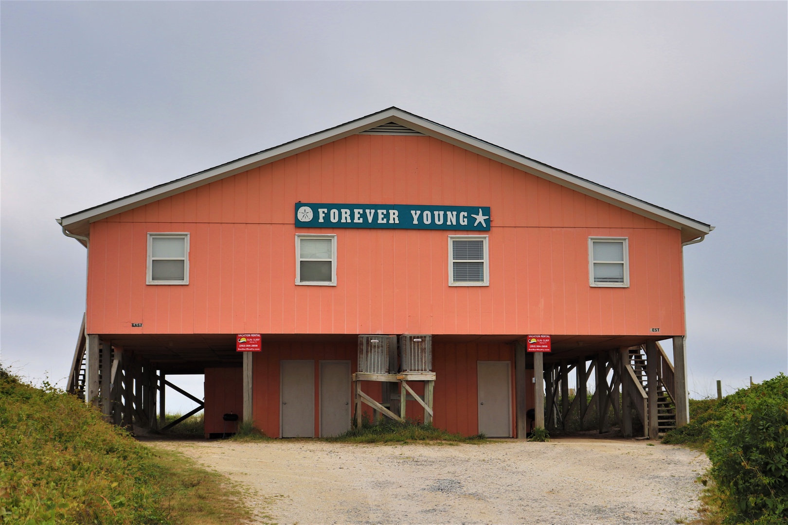 Charming coral-colored beachfront retreat on stilts, aptly named 'Forever Young' with dual entrances and coastal charm.