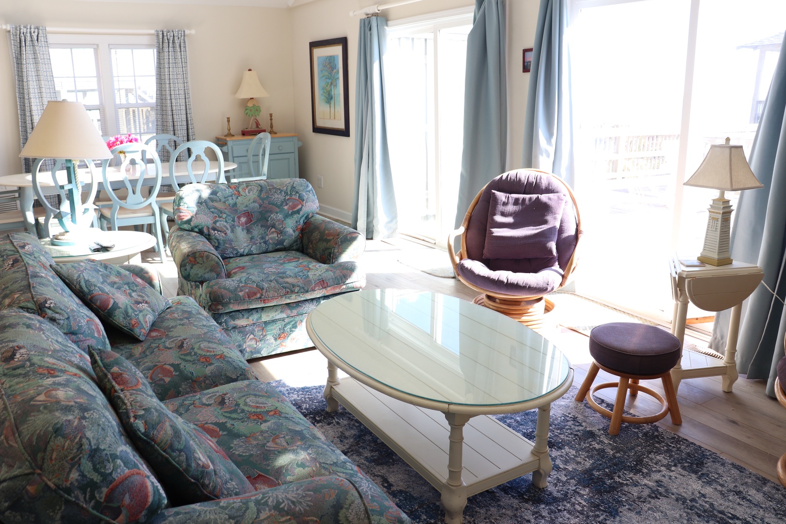 Settle into your bright, airy living space featuring soft coastal furnishings, a unique swivel chair, and glass doors opening to your private outdoor area.