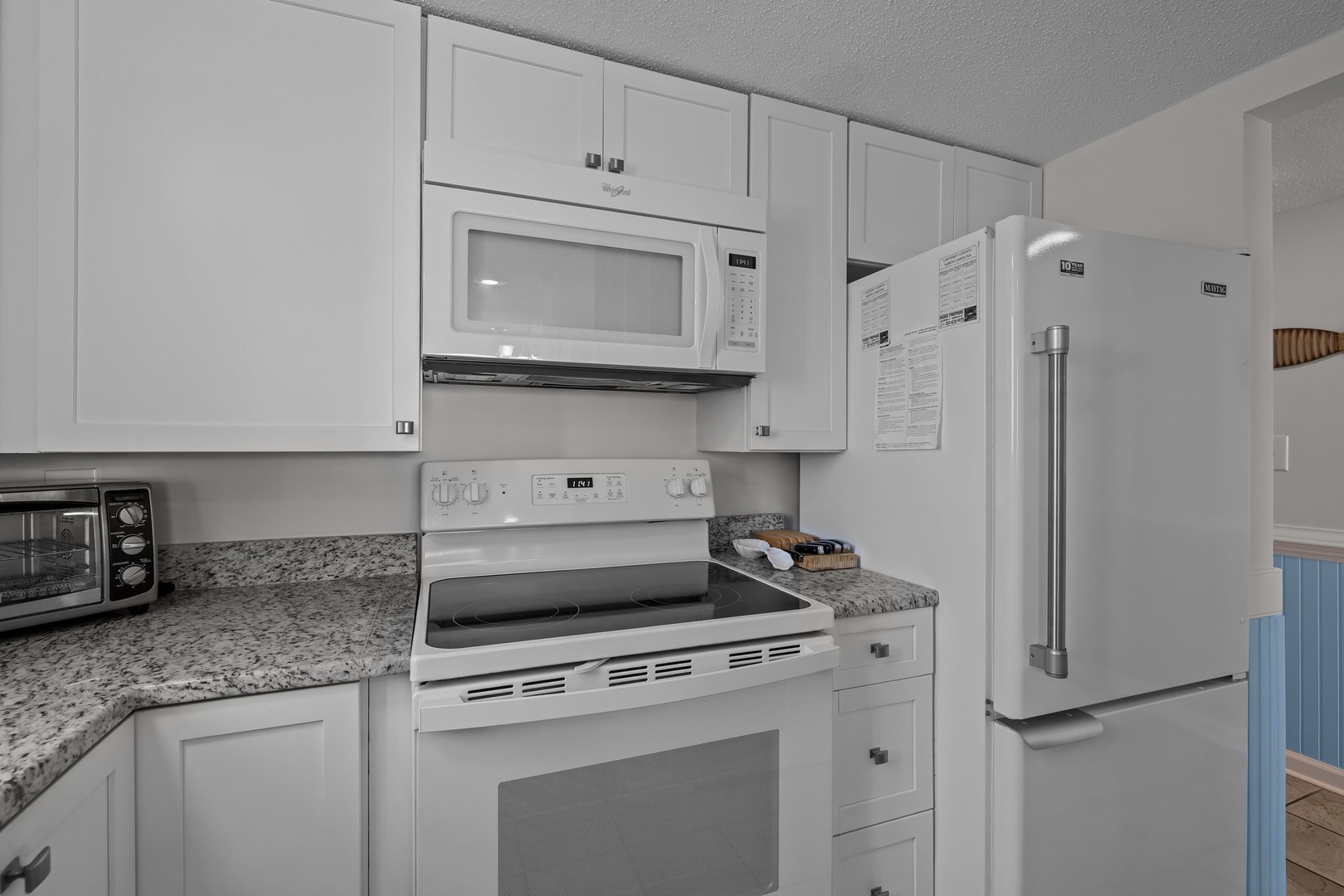 Your fully equipped kitchen features modern white appliances and granite countertops, perfect for preparing meals during your stay.