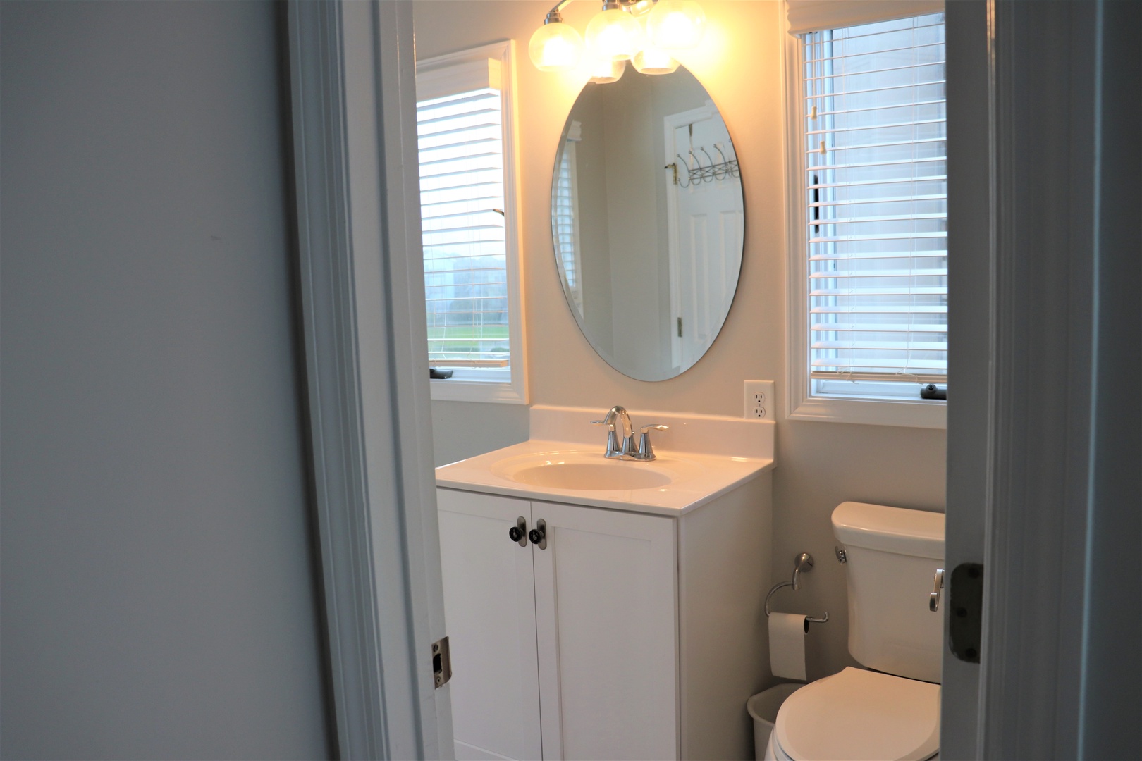Refresh in your bright, clean bathroom with natural light streaming through blinds, complete vanity, and modern fixtures.