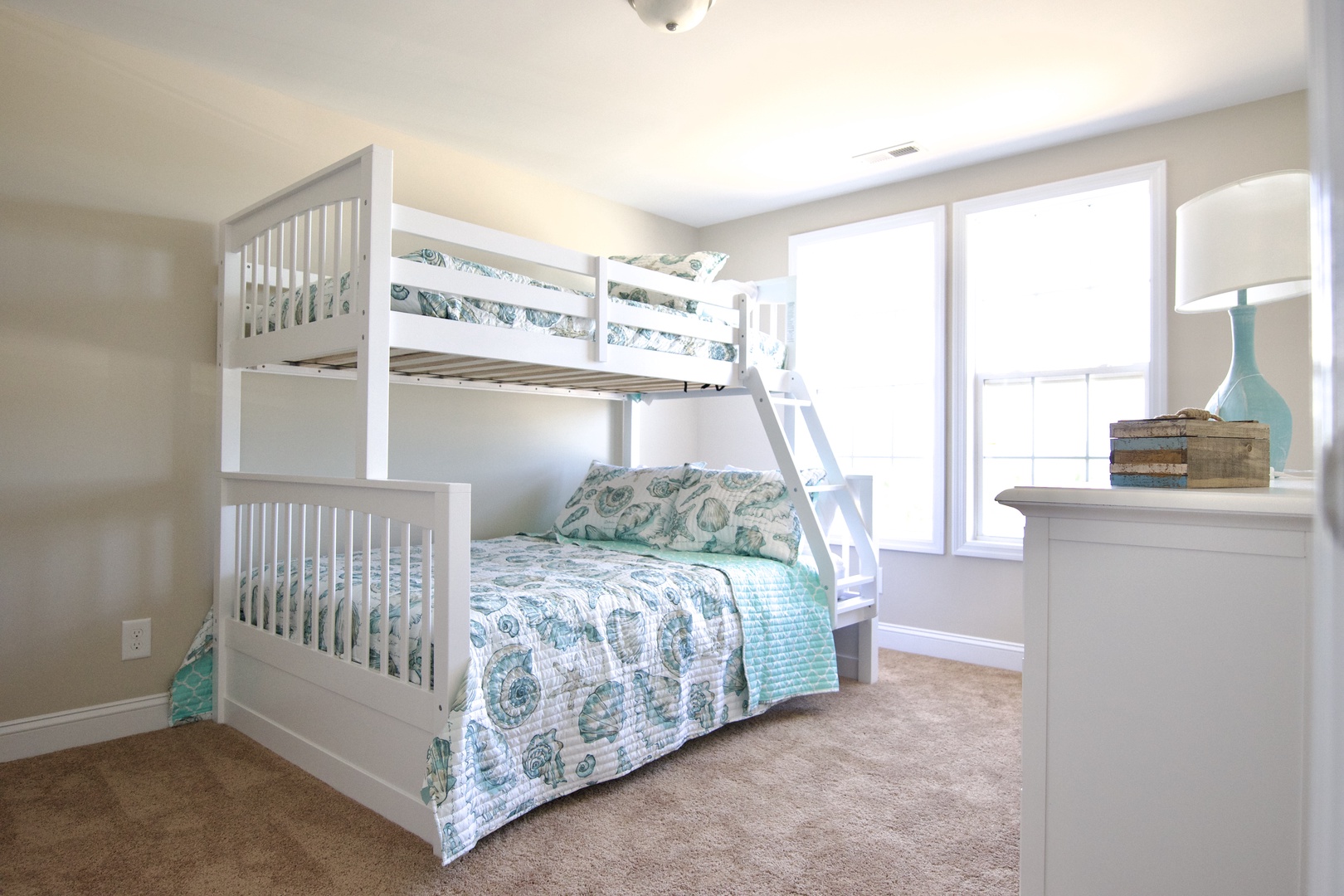 Unwind in this bright bedroom where cheerful coastal linens and natural light create your perfect retreat for restful nights.