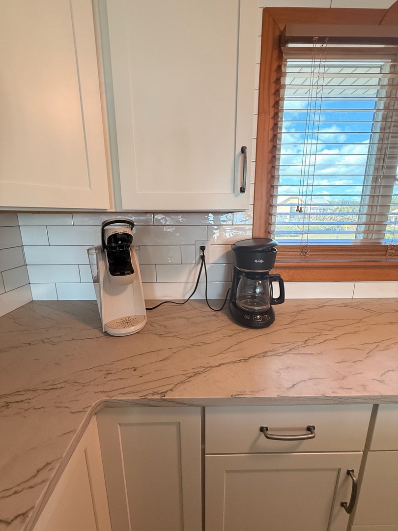 Brew your morning coffee in a bright kitchen featuring classic white cabinetry and beautiful marble countertops—perfect for preparing meals at your leisure.