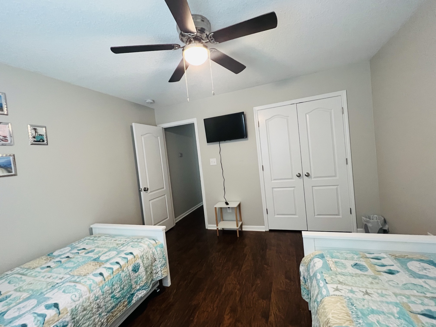 Your comfortable twin bedroom features coastal-themed bedding, a ceiling fan, and wall-mounted TV for peaceful relaxation after exploring.