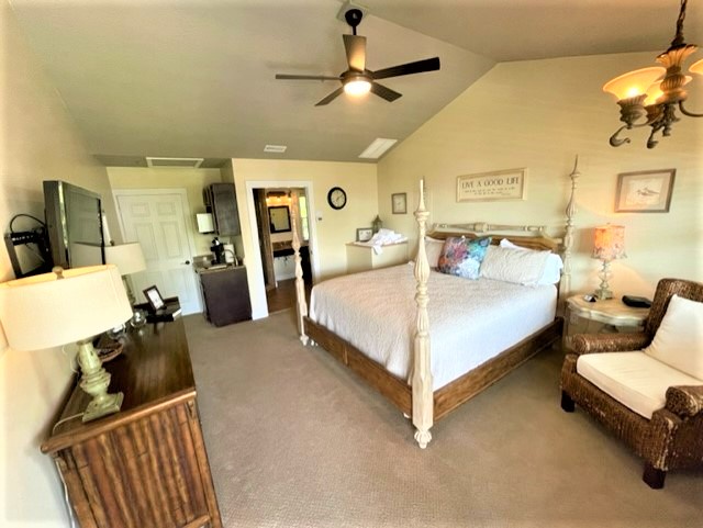Unwind in your spacious master bedroom featuring a charming four-poster bed and cozy wicker seating area perfect for quiet moments.