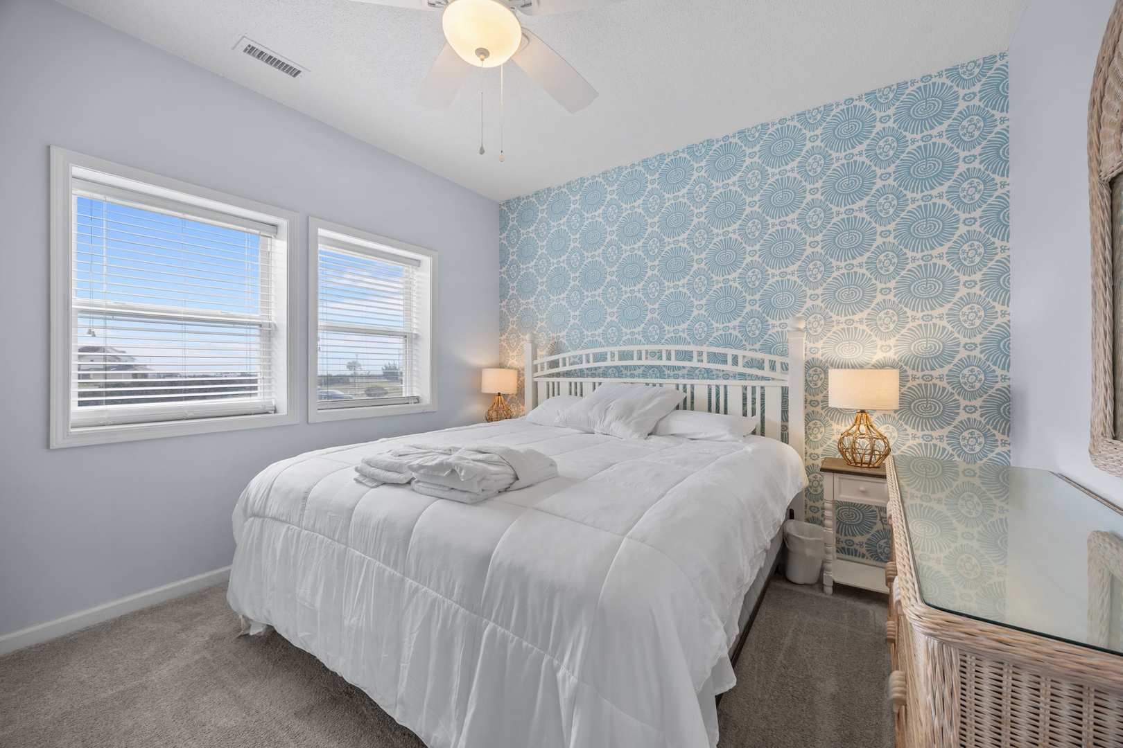 Drift into peaceful sleep in this serene bedroom featuring soft blue coastal wallpaper and crisp white linens.