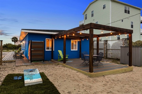 Your vibrant beachside retreat awaits with a private deck where string lights create magical evening ambiance for outdoor dining and relaxation.