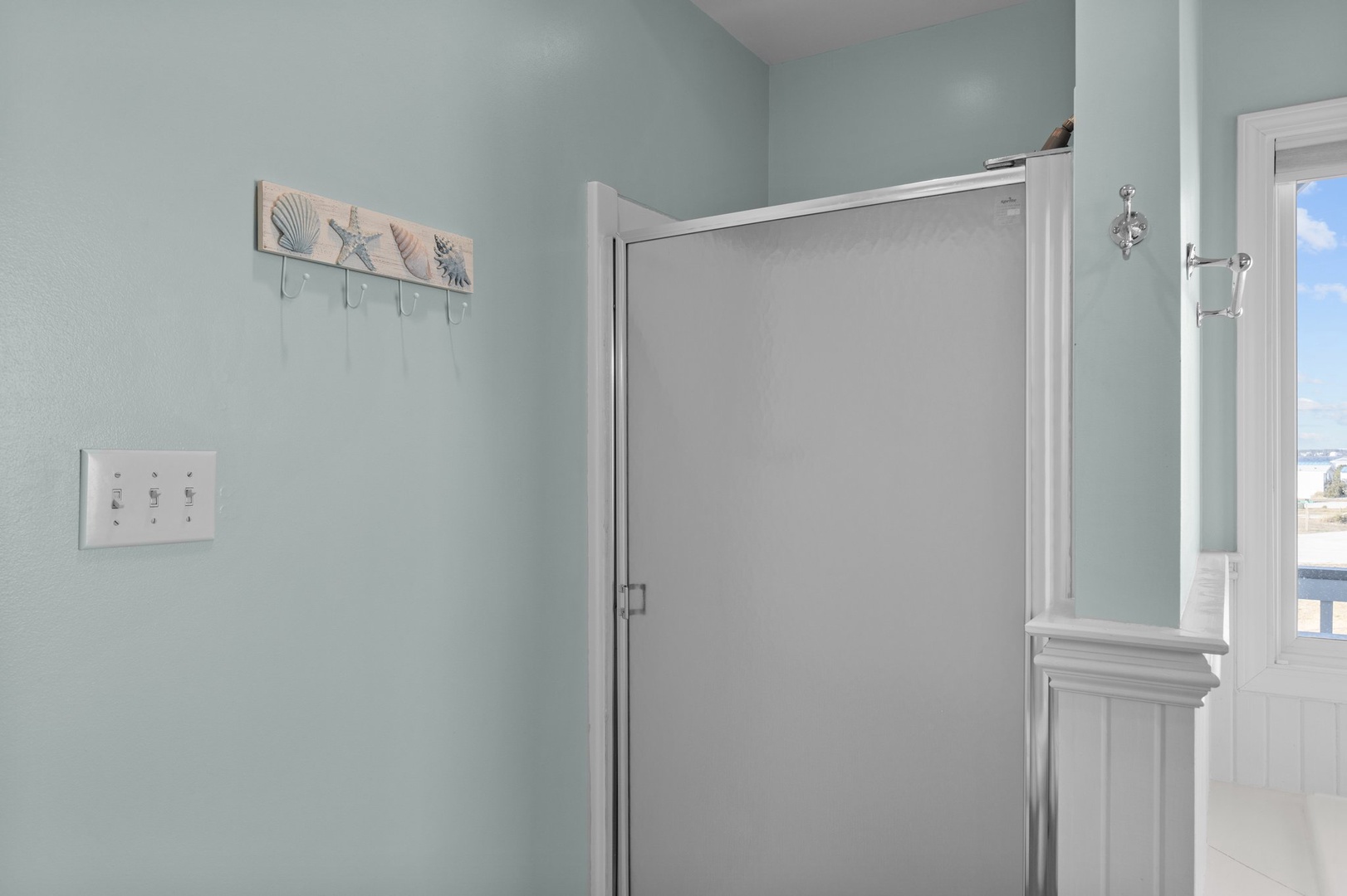 Your coastal-themed bedroom features a space-saving Murphy bed with nautical touches and soothing seafoam walls for ultimate relaxation.