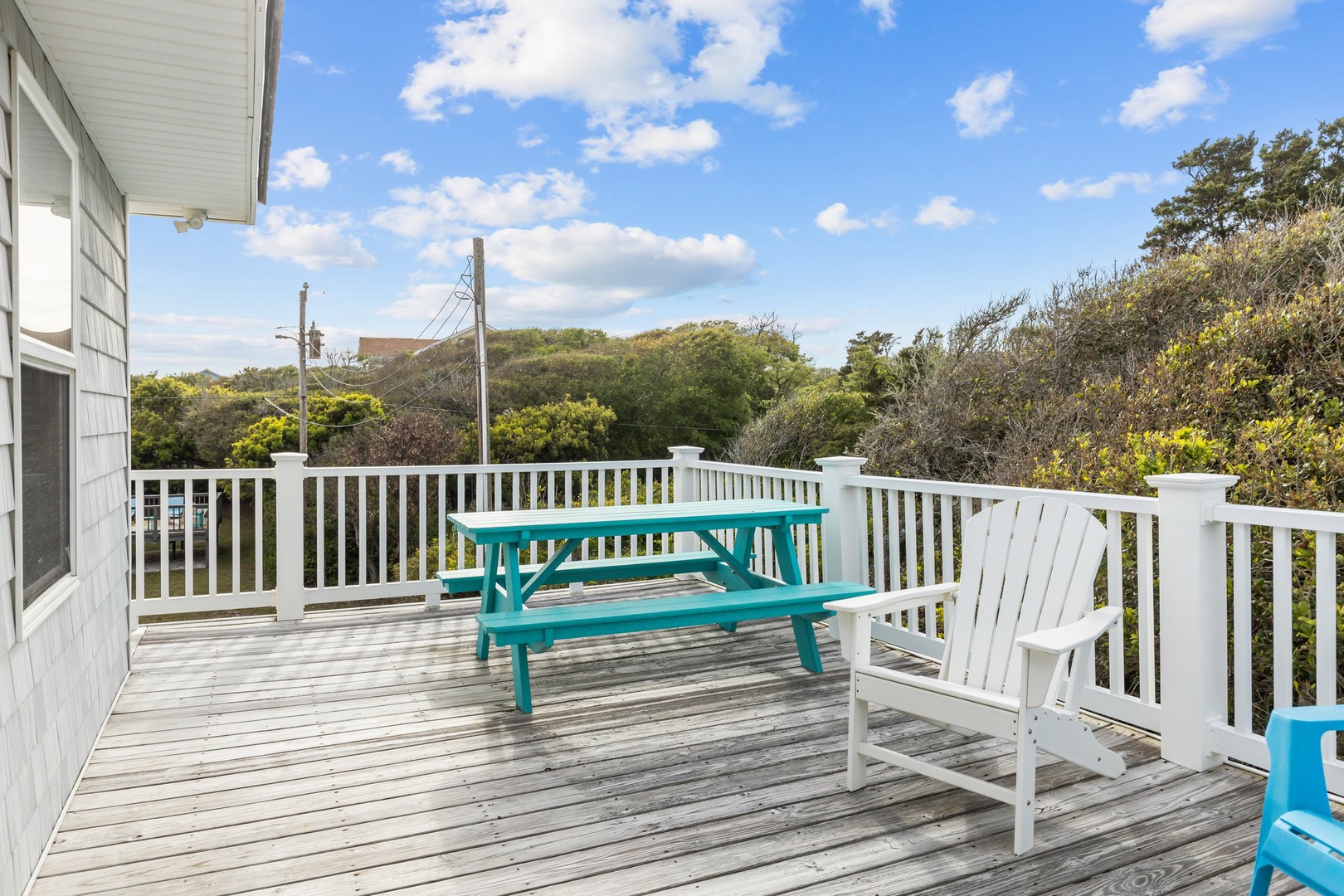 Spacious deck overlooks lush treetops under bright blue skies with comfortable seating for outdoor dining and relaxation.