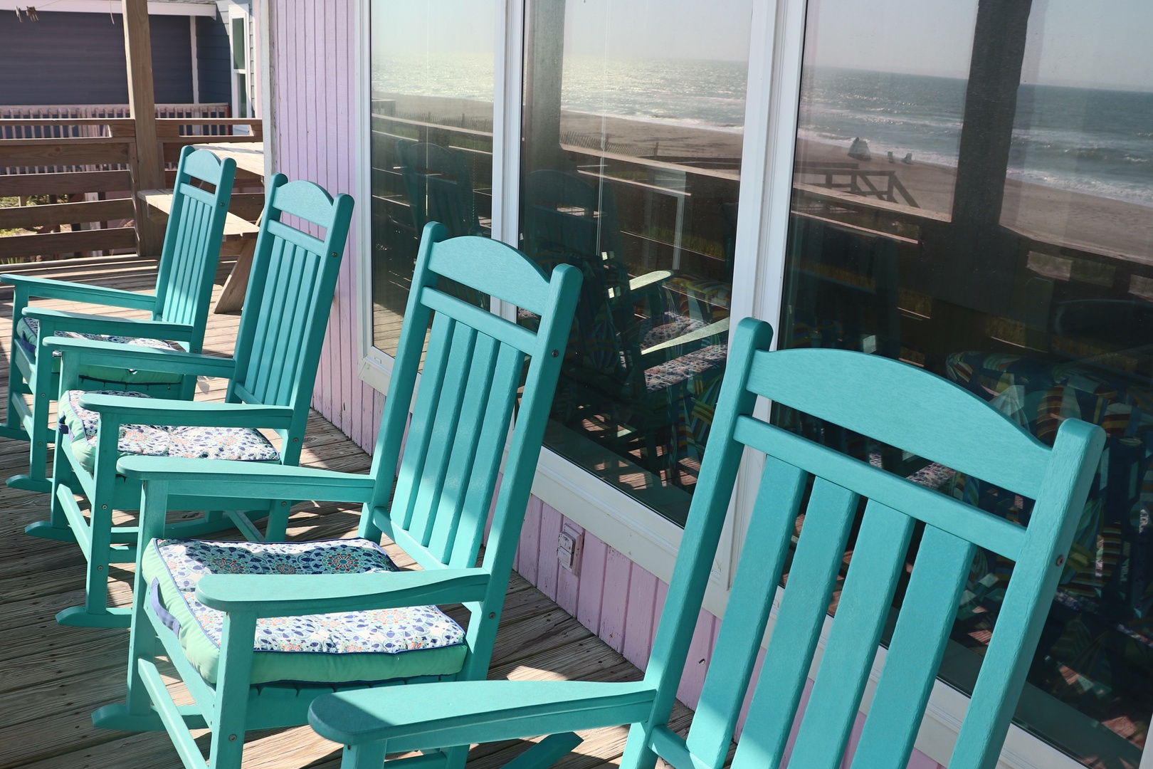 Settle into charming turquoise rocking chairs on your private deck, where ocean waves and coastal breezes create the perfect seaside retreat.
