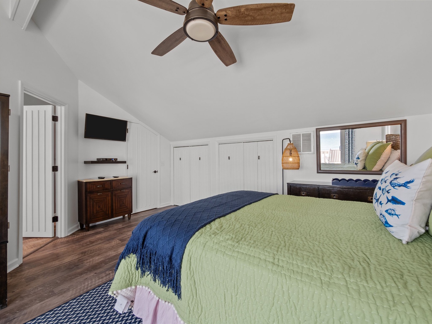 Unwind in your cozy bedroom featuring crisp linens, exposed beams, and a ceiling fan for perfect climate comfort.