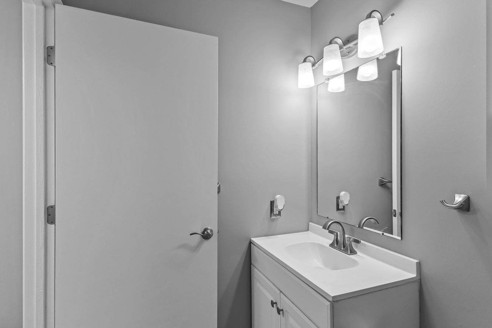 Fresh linens await in your private bathroom, complete with bright vanity lighting and modern fixtures for your comfort.