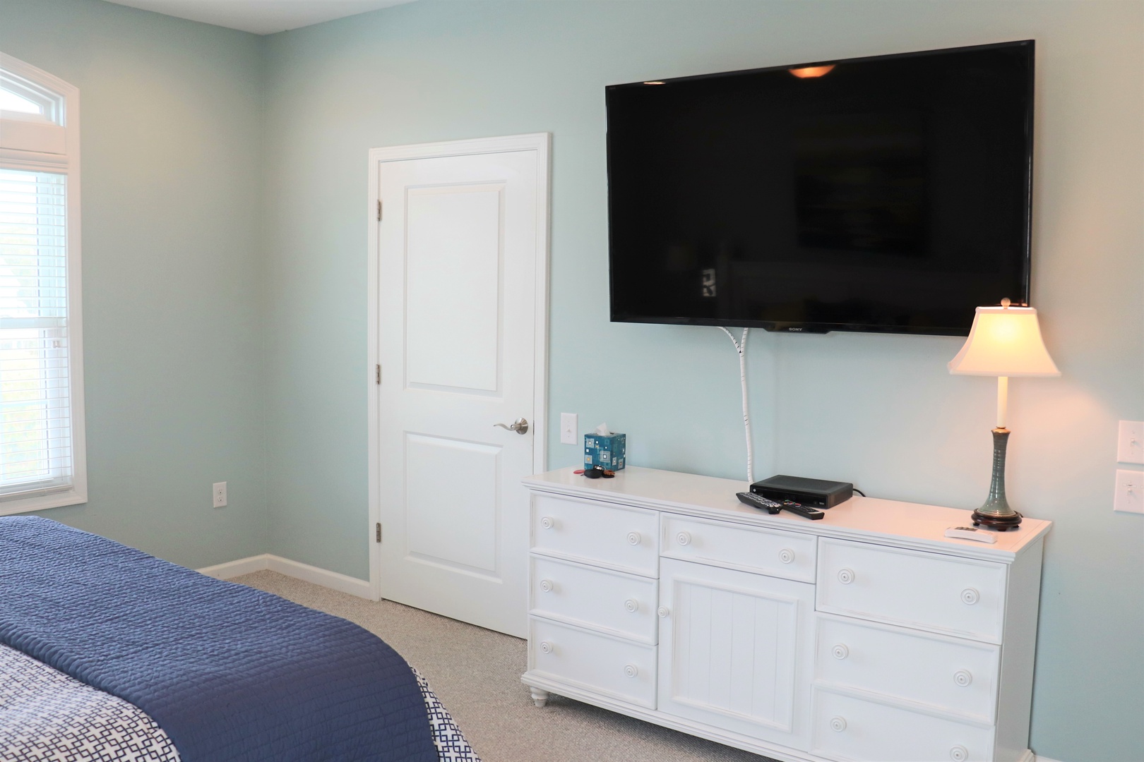 Relax in your serene bedroom with soothing mint walls, a large flat-screen TV, and elegant white dresser for all your belongings.