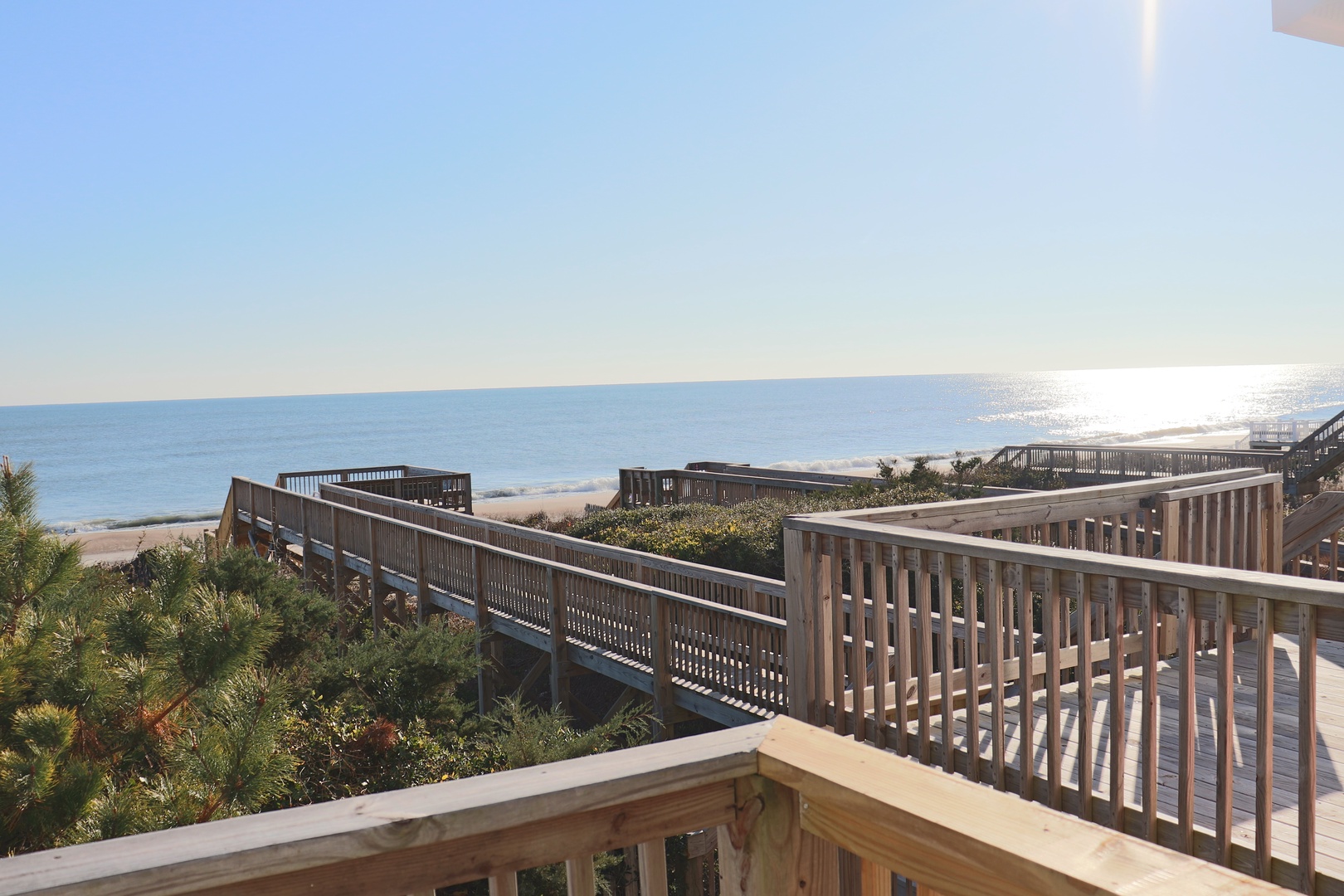 Elevated wooden walkways wind through coastal dunes toward pristine sandy shores, offering scenic beach access and ocean views.