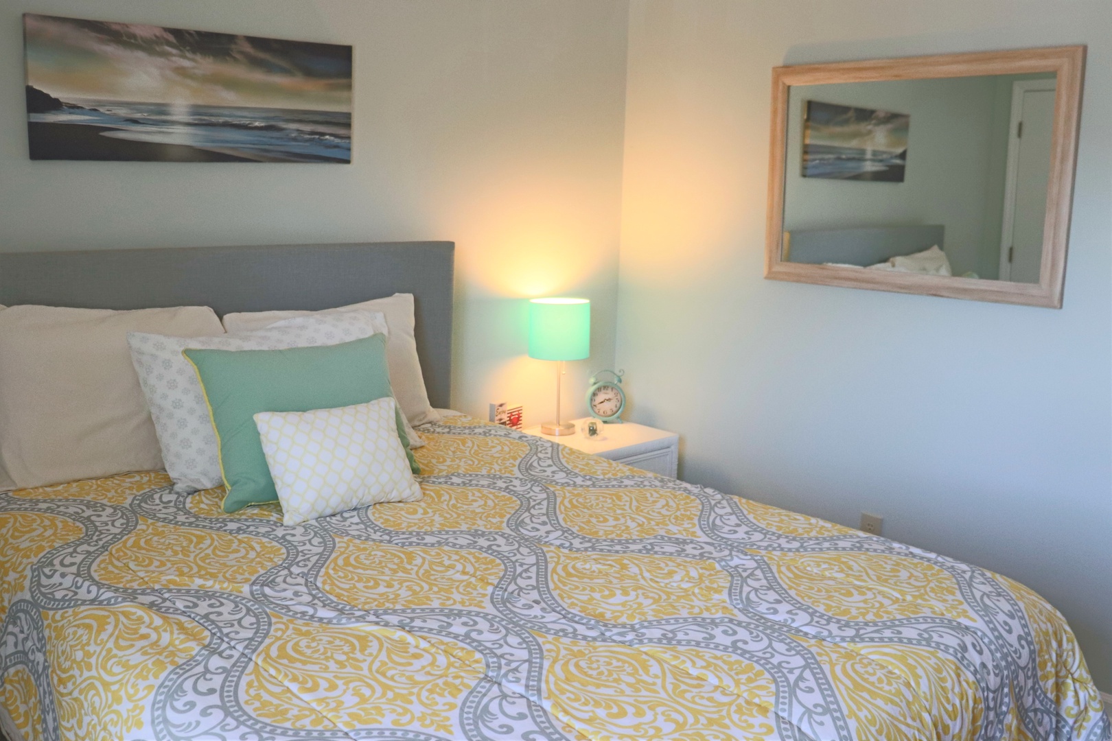 Drift into peaceful dreams surrounded by cheerful yellow patterns and coastal artwork in your serene bedroom retreat.