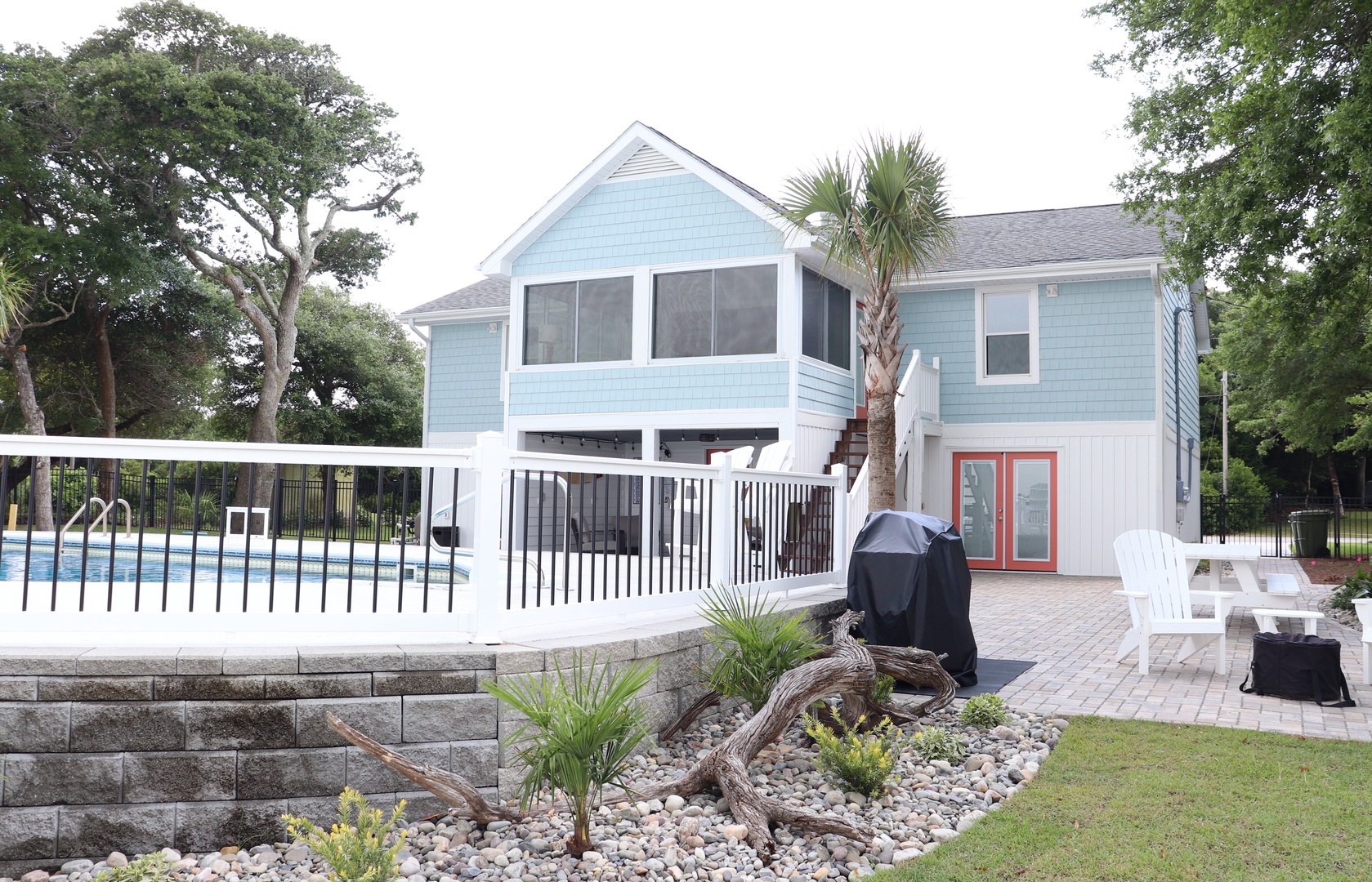 Coastal charm meets modern comfort at this elevated blue beach house with sparkling pool and tropical landscaping.