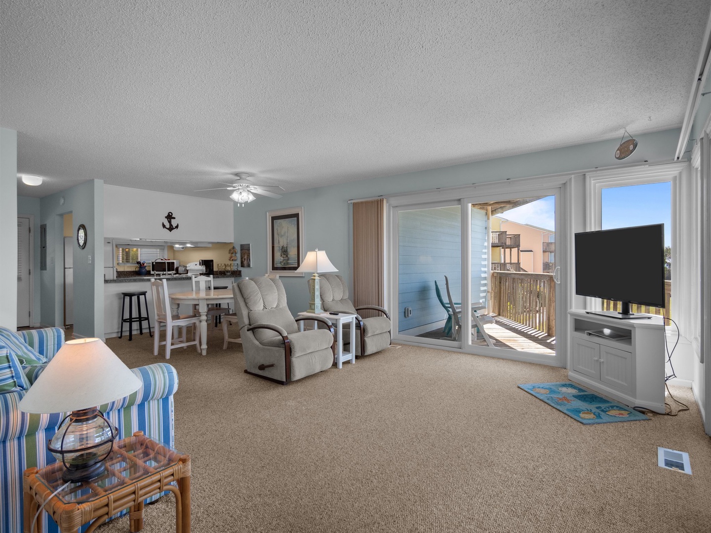 Sink into comfortable seating and enjoy your sea views through expansive windows. The open layout connects your living space to kitchen, perfect for seaside relaxation.