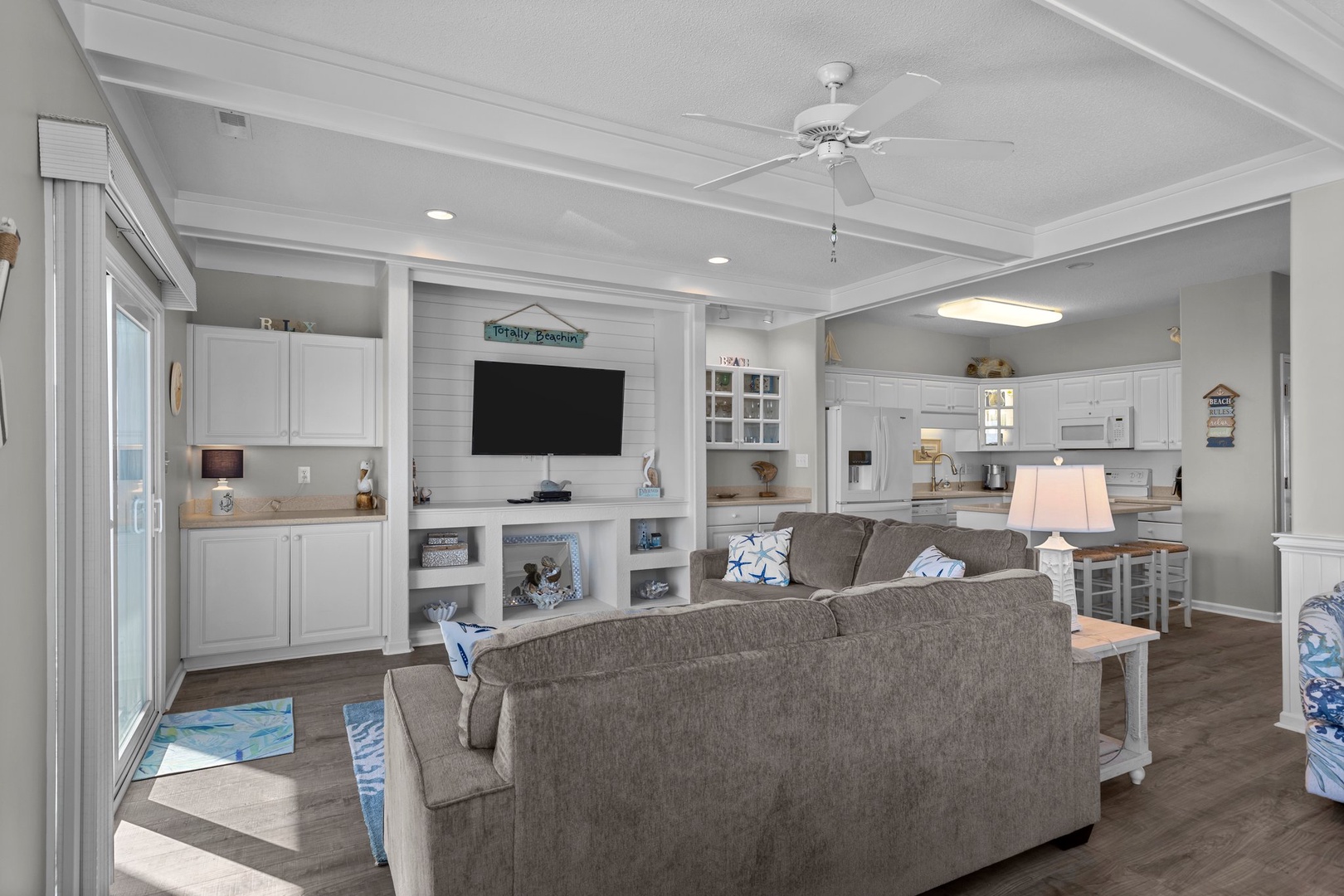 Relax in your bright, open-concept living space with comfortable seating, entertainment center, and fully equipped kitchen ready for your coastal getaway.