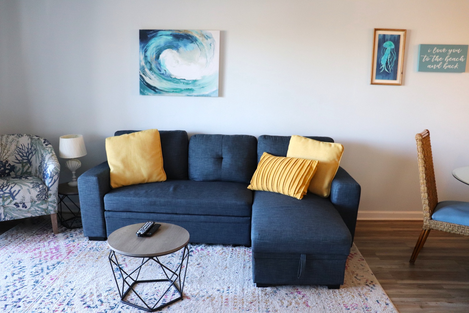 Sink into this cozy navy sectional with golden accents, where ocean-themed art sets a tranquil mood for your perfect getaway retreat.