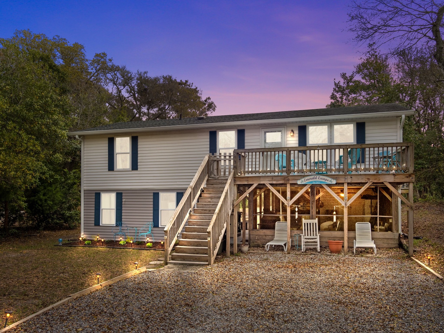 Charming two-story beach house with spacious deck and private parking, surrounded by mature trees in a peaceful wooded setting.