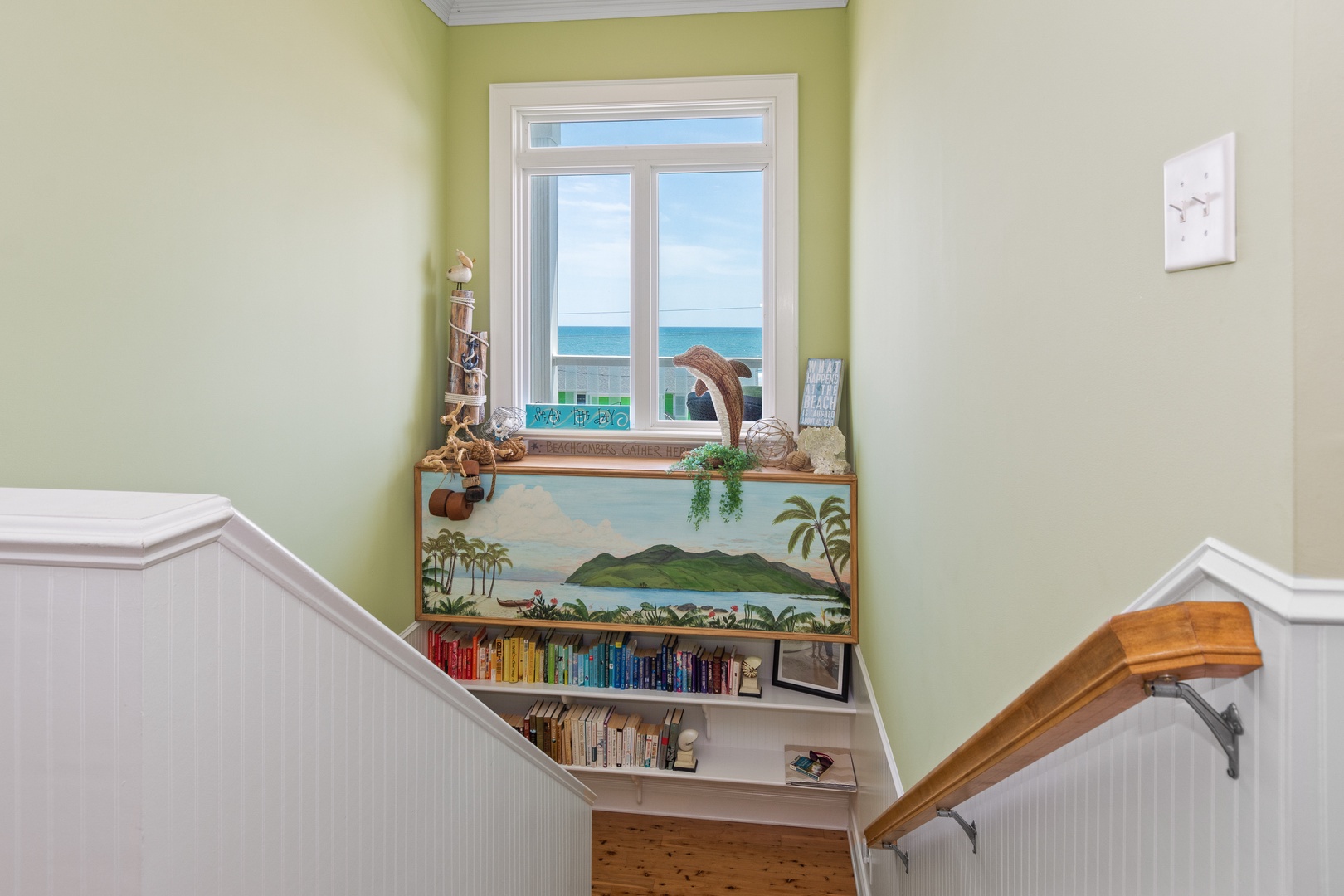 Your reading nook awaits with ocean views and tropical charm, where colorful books line the shelves beneath a hand-painted island mural.