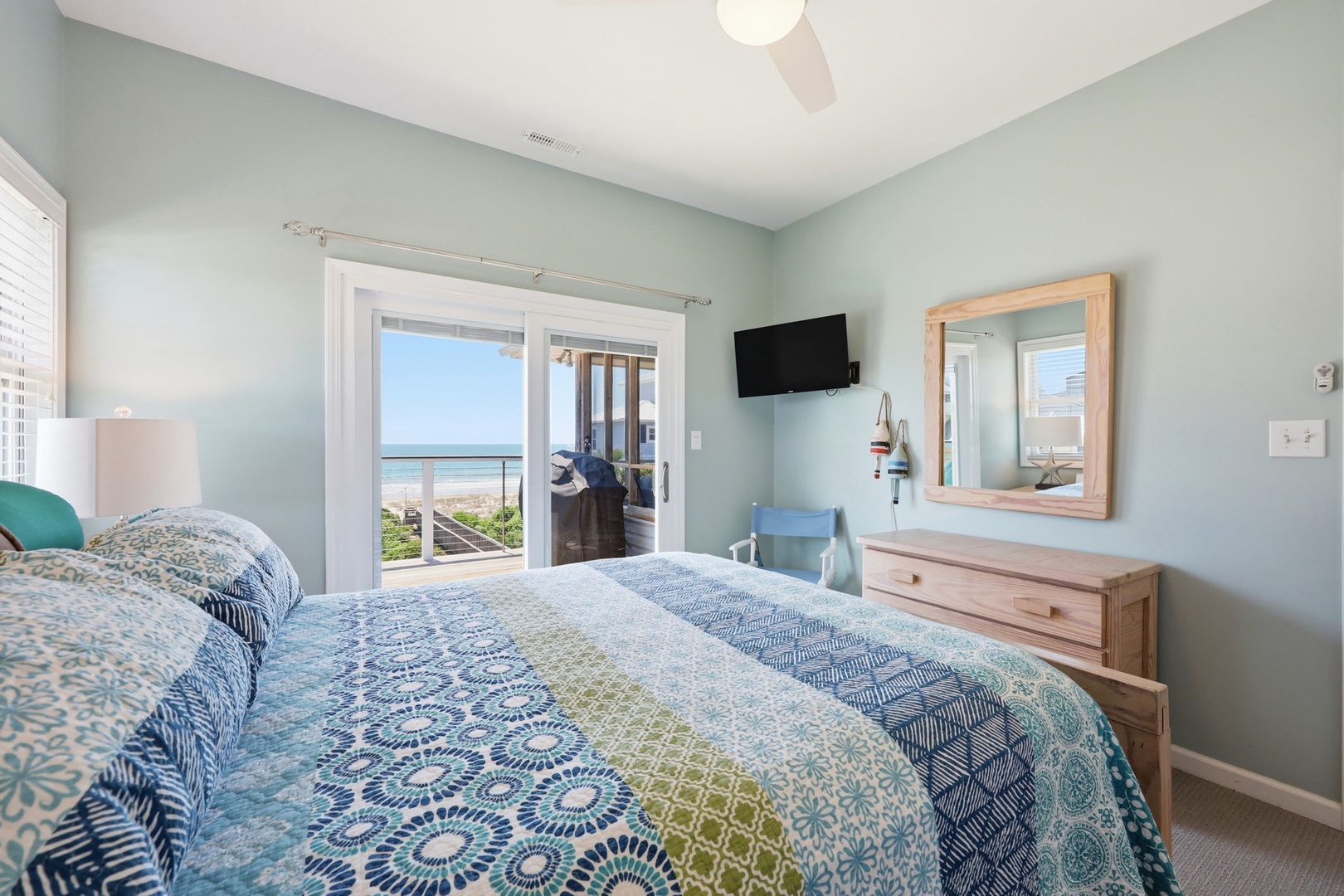 Drift off in your coastal bedroom with serene ocean views through the sliding doors. The soothing palette and comfortable bedding invite restful nights, while a smart TV adds convenience to your retreat.