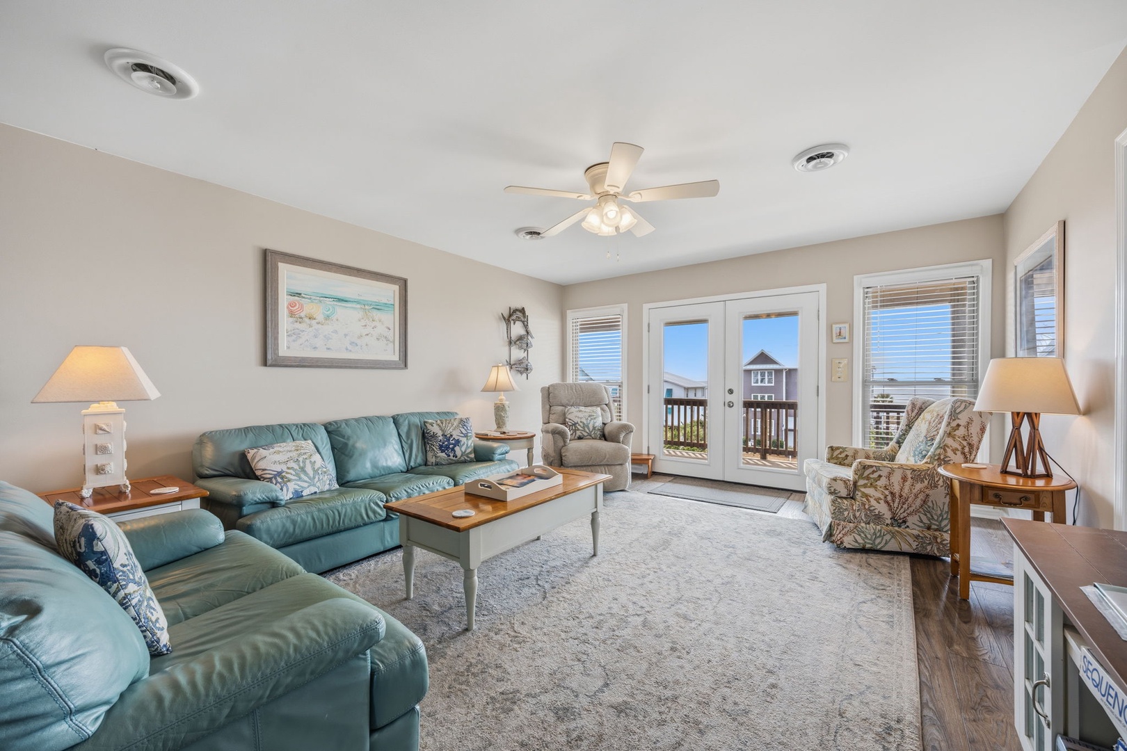 Relax in your spacious living room with turquoise leather seating, coastal artwork, and French doors opening to your private balcony overlooking the beach.
